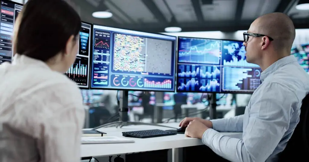 People analyzing data on multiple screens.