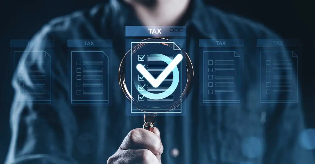 Illustration of a magnifying glass looking at tax compliance documents